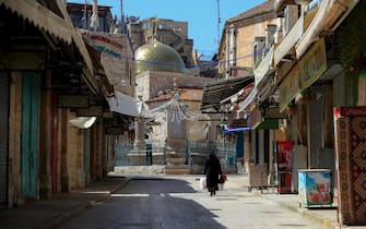 A woman makes her way past closed shops in the Old City of Jerusalem following the closure of the city for non-residents as a measure to contain the spead of the novel coronavirus, on March 29, 2020. (Photo by Emmanuel DUNAND / AFP)