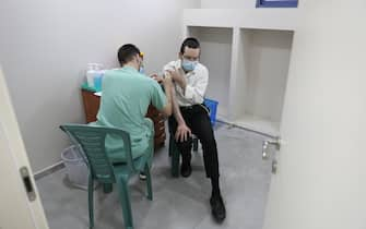 epa09004302 An Ultra orthodox Jewish man receives a COVID-19 vaccine from a nurse at Ichilov Medical Center in a Yeshiva at the Ultra orthodox city of Bnei Brak, Israel, 11 February 2021. Israel begin a vaccinations campaign at the ultra orthodox community, as Israel has so far vaccinated over three million of its around nine million citizens with the first dose of the coronavirus and two million have been given the second dose  EPA/ABIR SULTAN