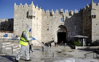 A municipal worker disinfects in front of the Damascus Gate in Jerusalem's Old City as a measure against the spread of coronavirus (COVID-19), on March 29, 2020. (Photo by Ahmad GHARABLI / AFP)