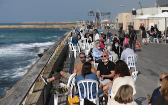 epa08993932 People enjoy a sunny day at the port of Tel Aviv, Israel, 07 February 2021. Israel is gradually lifting the restrictions after a full three weeks of a national lockdown, and although is one of the first countries to have received vaccines and has so far vaccinated more then three million of its around nine million citizens, the rate of infection with the Sars-CoV-2 coronavirus, that causes the coronavirus disease (COVID-19), is rising drastically .  EPA/ABIR SULTAN