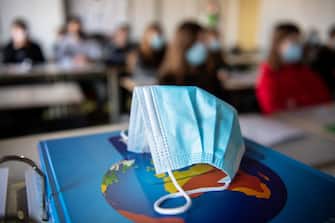 17 November 2020, Bavaria, Munich: ILLUSTRATION - A mouth and nose protector is in the classroom in a geography seminar in grade 11 at the state grammar school Trudering on a world atlas, while in the background the students with mouth and nose protectors can be seen. Photo: Matthias Balk/dpa (Photo by Matthias Balk/picture alliance via Getty Images)