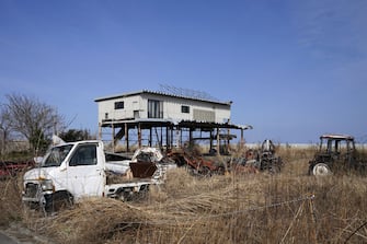 An abandoned building and vehicles on wasteland in Futaba, Fukushima Prefecture, Japan, on Tuesday, March 9, 2021. Laid waste by a nuclear disaster a decade ago, Japans Fukushima is still struggling to recover, even as the government tries to bring people and jobs back to former ghost towns by pouring in billions of dollars to decontaminate and rebuild. Photographer: Toru Hanai/Bloomberg via Getty Images