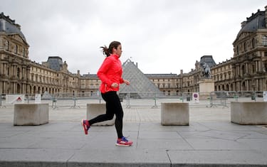 PARIS, FRANCE - MARCH 17: A jogger runs near the Napoleon's deserted courtyard in front of the pyramid and the closed Louvre Museum one year to the day after the start of the first lockdown as the coronavirus disease (COVID-19) outbreak continues on March 17, 2021 in Paris, France. French Prime minister, Jean Castex said on 16 March 2021 on BFM Television that the situation was "worrying and critical" and that time had come for additional coronavirus restrictions. New restrictions and local or partial lockdown could be taken in several French regions, including Ile-de-France. (Photo by Chesnot/Getty Images)
