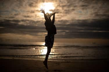 LIVERPOOL, UNITED KINGDOM - AUGUST 21:  A young muslim girl dances and runs in the sea as she and her family celebrate Eid Al-Adha by watching the sunset at Crosby beach on August 21, 2018 in Liverpool, England. The traditional four-day celebratory festival marks one of the holiest days in the Islamic religious calendar.  (Photo by Christopher Furlong/Getty Images)