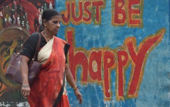 An Indian woman walks past wall graffiti in Mumbai on March 16, 2018. 
The annual World Happiness Report 2018? by United Nations Sustainable Development Solutions Network released this week puts India at a lowly 133 on the list of 156 countries. The Report is a landmark survey of the state of global happiness and ranks 156 countries by their happiness levels, and 117 countries by the happiness of their immigrants. / AFP PHOTO / Indranil MUKHERJEE        (Photo credit should read INDRANIL MUKHERJEE/AFP via Getty Images)