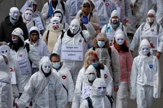 Protesters dressed in white take part in a demonstration against the ongoing coronavirus Covid-19 restrictions in Liestal, near Basel, on March 20, 2021. - Between 3,000 and 5,000 people, some of them wearing white suits, take part in a 'silent demonstration on March 20, 2021 in Liestal, Northern Switzerland, demanding an end to restrictions designed to contain the Covid-19 pandemic. (Photo by STEFAN WERMUTH / AFP) (Photo by STEFAN WERMUTH/AFP via Getty Images)