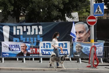 epa09090086 A women walks near posters supporting Israeli Prime Minister and leader of the Likud party Benjamin Netanyahu outside his residence in Jerusalem, Israel, 22 March 2021. Israel is expected to hold legislative elections on 23 March 2021 to elect the members of the 24th Knesset.  EPA/ABIR SULTAN