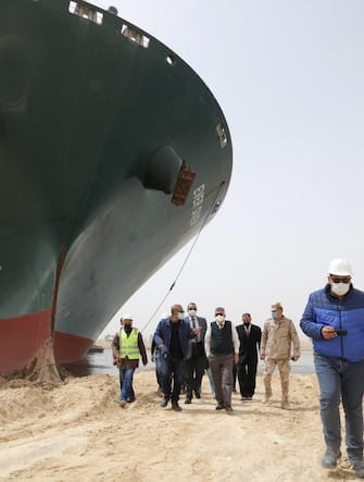 epa09095775 A handout photo made available by the Suez Canal Authority, shows officials and workers assessing the situation near the Ever Given container ship  which ran agorund in the Suez Canal, Egypt, 25 March 2021. the Ever Given, a large container ship ran aground in the Suez Canal on 23 March, blocking passage of other ships and causing a traffic jam for cargo vessels.  The head of the Suez Canal Authority announced on 25 March that "the navigation through the Suez Canal is temporarily suspended" until the floatation of the Ever Given is completed. Its floatation is being carried out by 8 large tugboats that are towing and pushing the grounding vessel.  EPA/SUEZ CANAL AUTHORITY/HO EDITORIAL USE ONLY NO SALES HANDOUT EDITORIAL USE ONLY/NO SALES