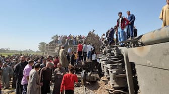 People gather around the wreckage of two trains that collided in the Tahta district of Sohag province, some 460 kms (285 miles) south of the Egyptian capital Cairo, reportedly killing at least 32 people and injuring scores of others, on March 26, 2021. - Egypt has been plagued with deadly train accidents in recent years that have been widely blamed on inadequate infrastructure and poor maintenance. (Photo by - / AFP) (Photo by -/AFP via Getty Images)