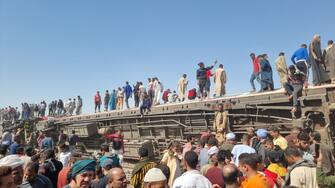 26 March 2021, Egypt, Tahta: People gather to inspect damaged train cars after two passenger trains collided near Tahta in Sohag Governorate. Egyptian media said the the collision caused some carriages to derail, killing at least 32 people and injuring dozens others. (best quality available) Photo: Mahmoud Maqboul/dpa (Photo by Mahmoud Maqboul/picture alliance via Getty Images)