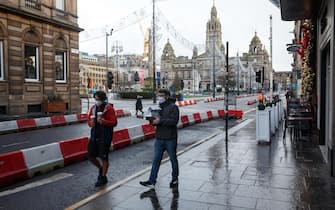epa08920664 Two men carry take-away food at George Square, during the first day in new lockdown in Glasgow, Scotland, Britain, 05 January 2021. Scotland has gone into lockdown due to increasing number of Covid-19 cases.  EPA/Robert Perry