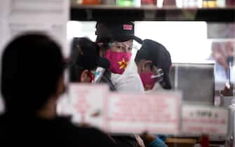 epa09045549 Employees wearing masks prepare the orders at Pink's Hot Dog as the restaurant reopens for pick-up and outdoor dining in Hollywood, California, USA, 01 March 2021. Pink's closed its doors for the past two months due to the increase in numbers of coronavirus cases concerned about the Covid-19 surge in order to keep patrons and staff safe.  EPA/ETIENNE LAURENT