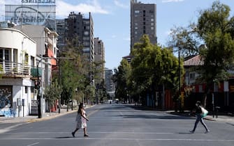 epa09088820 Two women walk down a semi-empty avenue in Santiago, Chile, 21 March 2021. The city is in a new mandatory quarantine day decreed due to the advance of COVID-19, despite the fact that Chile is among the leading countries in the world in the administration of the vaccine per 100 inhabitants.  EPA/Alberto Valdes