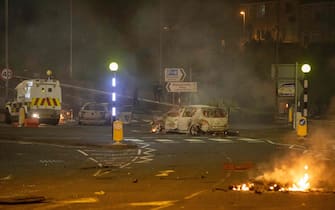 A burnt out car and flames are seen at the scene of violence in Newtownabbey, north of Belfast, in Northern Ireland on April 3, 2021. - The disturbance in the Loyalist area north of Belfast, where petrol bombs were thrown and cars were set alight, follows a night of violence in the Northern Ireland capital in which police officers were injured prompting calls for calm. It is thought rising discontent among unionist pro-British factions in Northern Ireland over arrangements aimed at preserving a fragile peace in the territory by preventing a hard border with EU member Ireland is fueling anger. Tension has also been stoked this week by a decision not to prosecute 24 Sinn Fein party members who attended the funeral in June of Irish Republican Army figure Bobby Storey in blatant violation of of Covid-19 guidelines. (Photo by PAUL FAITH / AFP) (Photo by PAUL FAITH/AFP via Getty Images)