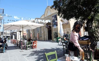 epa09077902 A waitress cleans the table outside a re-opened cafe in Nicosia, Cyprus, 16 March 2021. Cyprus government removed some restrictions imposed to contain the ongoing coronavirus COVID-19 pandemic with some businesses allowed to re-open following strict rules for hygiene and safe distance.  EPA/KATIA CHRISTODOULOU