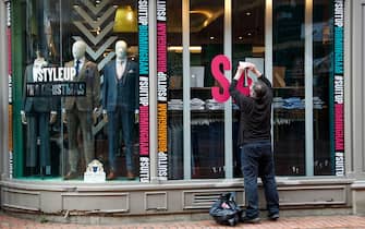 A worker removes a 'Sale' sign from the window of a Suit Direct store in Birmingham, U.K., on Monday, April 12, 2021. Non-essential retailers as well as pubs and restaurants with outdoor space will reopen Monday across England after almost 100 days of lockdown, hoping pent-up demand will translate into strong sales. Photographer: Darren Staples/Bloomberg via Getty Images
