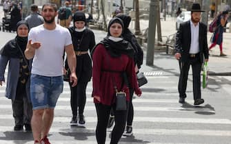 People walk on a street in Jerusalem, on April 18, 2021, after Israeli authorities announced that face masks for COVID-19 prevention were no longer required outdoors. - With over half the population fully vaccinated in one of the world's fastest anti-COVID19 inoculation campaigns, Israel's coronavirus caseload tumbled from some 10,000 new infections per day as recently as mid-January, to around 200 cases a day, prompting an announcement by the Health Ministry on April 15 that face masks are no longer compulsory outdoors. (Photo by menahem kahana / AFP) (Photo by MENAHEM KAHANA/AFP via Getty Images)