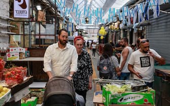 People shop in a market in Jerusalem, on April 18, 2021, after Israeli authorities announced that face masks for COVID-19 prevention were no longer required outdoors. - With over half the population fully vaccinated in one of the world's fastest anti-COVID19 inoculation campaigns, Israel's coronavirus caseload tumbled from some 10,000 new infections per day as recently as mid-January, to around 200 cases a day, prompting an announcement by the Health Ministry on April 15 that face masks are no longer compulsory outdoors. (Photo by menahem kahana / AFP) (Photo by MENAHEM KAHANA/AFP via Getty Images)