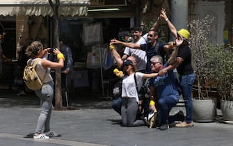 People pose for a picture on a street in Jerusalem, on April 18, 2021, after Israeli authorities announced that face masks for COVID-19 prevention were no longer required outdoors. - With over half the population fully vaccinated in one of the world's fastest anti-COVID19 inoculation campaigns, Israel's coronavirus caseload tumbled from some 10,000 new infections per day as recently as mid-January, to around 200 cases a day, prompting an announcement by the Health Ministry on April 15 that face masks are no longer compulsory outdoors. (Photo by menahem kahana / AFP) (Photo by MENAHEM KAHANA/AFP via Getty Images)