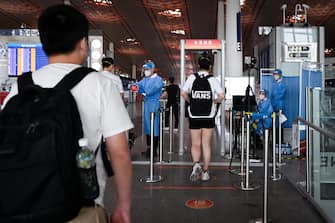 Travellers walk through a temperature monitoring device at Beijing's international airport on June 17, 2020. - Beijing's airports cancelled more than 1,200 flights and schools in the Chinese capital were closed again on June 17 as authorities rushed to contain a new coronavirus outbreak linked to a wholesale food market. (Photo by STR / AFP)