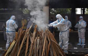 epa09167973 Family members, wearing Personal Protective Equipment (PPE), perform the last rites for COVID-19 victims during their funeral at a cremation ground in New Delhi, India, 29 April 2021. Delhi reported 25,986 fresh cases, 368 deaths in last 24 hours and continue to struggle with the oxygen supply.  EPA/IDREES MOHAMMED
