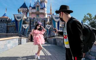 Anaheim, CA, Friday, April 30, 2021 -Minerva Mendez and Ahmed El take photos in front of Sleeping Beautys Castle as a limited number of people come to Disneyland the first day after closing more than a year ago.  (Robert Gauthier/Los Angeles Times via Getty Images)