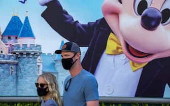 ANAHEIM, CA - APRIL 30: People enter Disneyland Park as it reopens for the first time since the COVID 19 pandemic forced the park to shut down last year on April 30, 2021 in Anaheim, California. California saw some of the highest infection rates in the nation over the winter but now enjoys some of the lowest. Los Angeles County, for example, is now expected to move from the orange tier of the states economic reopening system based on COVID-19 metrics to the least restrictive yellow tier, which would allow greater reopening freedoms, as early as next week.  (Photo by David McNew/Getty Images)