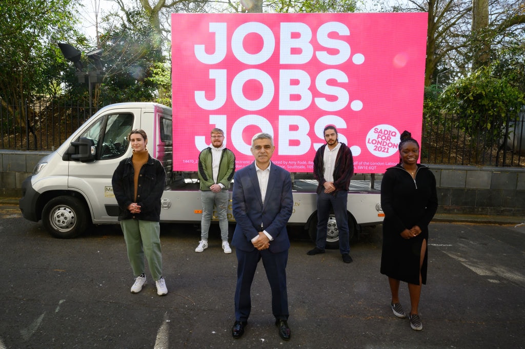1309903613 LONDON, ENGLAND - MARCH 30: Mayor of London Sadiq Khan poses for photographers in front of a poster stating his Mayoral campaign pledge of "Jobs Jobs Jobs" on March 30, 2021 in London, England. Candidates for the London Mayoral election include incumbent Sadiq Khan for the Labour Party, Shaun Bailey - Conservative, Kam Balayev - Renew, Sian Berry - Green Party, Laurence Fox - Reclaim Party, Peter Gammons - UKIP, Luisa Porritt - Liberal Democrats and Mandu Reid - Women's Equality Party alongside a number of Independents. Londoners will go to the polls on Thursday, May 6, 2021. (Photo by Leon Neal/Getty Images)