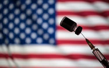 POLAND - 2021/01/24: In this photo illustration a vial of COVID-19 vaccine and a medical syringe displayed over an American flag. (Photo Illustration by Vito Corleone/SOPA Images/LightRocket via Getty Images)