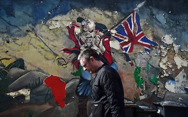 LONDONDERRY, NORTHERN IRELAND - MAY 04: A man walks past a mural marking unionist territory on May 4, 2016 in Londonderry, Northern Ireland. The city of Londonderry is situated on the border between the north and south of Ireland. Flags, murals or kerbstone painting are sometimes the first visual indication of the border having been crossed. The United Kingdom has just one external land border which is located between Northern Ireland and the Republic of Ireland. At present there are no checkpoints in place for anyone crossing this border, either by foot or vehicle. Prior to the Anglo-Irish agreement anyone wishing to cross the border was subjected to armed checkpoints while unguarded country roads were blocked by concrete barricades. With the Brexit referendum taking place on June 23 to decide whether Britain should remain in the European Union some politicians have warned that the open border could be used as a possible backdoor entrance by migrants, traffickers and criminals wishing to gain access to the UK following a decision to leave the EU. (Photo by Charles McQuillan/Getty Images)