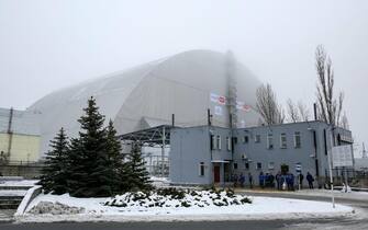 epa05685631 Workers wait for a bus next to the new protective shelter over the remains of the nuclear reactor Unit 4, at Chernobyl nuclear power plant, in Chernobyl, Ukraine, 22 December 2016. The new mobile structure will secure the affected fourth reactor. The shelter is over 105 metres tall and weighs 36,000 tons. The explosion of Unit 4 of the Chernobyl nuclear power plant in the early hours of 26 April 1986 is still regarded the biggest accident in the history of nuclear power generation.  EPA/ROMAN PILIPEY