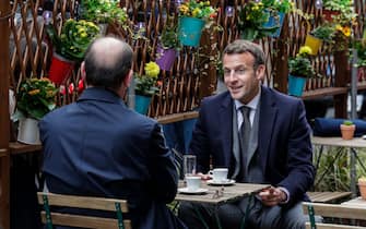 TOPSHOT - French President Emmanuel Macron (R) and French Prime Minister Jean Castex (L) are having coffees at a cafe terrace in Paris on May 19, 2021, as restaurant and bar terraces reopen today at 50-percent capacity for groups of up to six while the curfew will be pushed back from 7 to 9:00 pm, as part of an easing of the nationwide lockdown due to the Covid-19 pandemic. - Cafes and restaurants with terraces or rooftop gardens have been inundated with bookings for the return of outdoor dining, under the second phase of a lockdown-lifting plan that should culminate in a full reopening of the economy on June 30. Museums, cinemas and theatres are also reopening after being closed for more than six months, during which they relied chiefly on state aid to remain afloat. (Photo by GEOFFROY VAN DER HASSELT / AFP) (Photo by GEOFFROY VAN DER HASSELT/AFP via Getty Images)