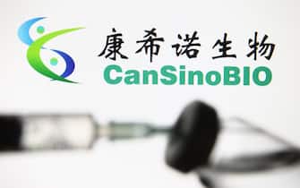 Una siringa e una dose di vaccino, sullo sfondo il logo dell'azienda cinese CanSino Biologics