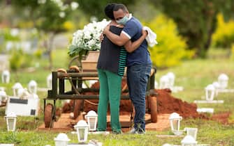 Due persone si abbracciano dopo la sepoltura di una persona cara vittima di Covid-19 al cimitero di Campo da Esperança, nella città di Brasilia, Brasile