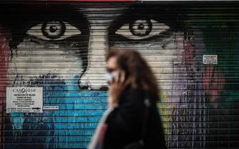 Una donna passeggia per le strade del centro di Buenos Aires, sullo sfondo un murales su una saracinesca di un negozio chiuso