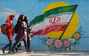 TOPSHOT - Young girls walk in front of a mural showing the Iranian national flag in the centre of the  capital Tehran, on April 23, 2019. - The White House announced yesterday it was calling an end to six-month waivers that had exempted several countries from unilateral US sanctions on Iranian oil exports. (Photo by ATTA KENARE / AFP)        (Photo credit should read ATTA KENARE/AFP via Getty Images)