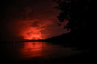 This general view taken on May 22, 2021 from Tchegera Island outsoide Goma on the lake Kivu in the East of the Democratic Republic of Congo shows flame spewing from the Nyiragongo volcano. - The famous Nyiragongo volcano, near the city of Goma, in the east of the Democratic Republic of the Congo (DRC), suddenly became active on Saturday evening, an AFP correspondent noted. Strong emanations of glowing light coming out of the crater were visible from Goma, while a smell of sulfur was perceptible in the city, located on the southern flank of the volcano, on the shores of Lake Kivu, he noted. (Photo by Alex Miles / AFP)