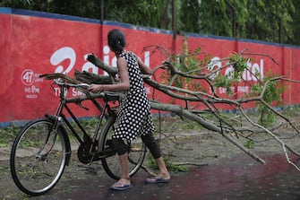 epa09228578 A woman carries fallen branches as Cyclone Yaas makes landfall in Digha, near the Bay of Bengal, south of Kolkata, India, 26 May 2021. The Odisha and Bengal governments started the evacuation of at-risk areas, as Cyclone Yaas hits the eastern coast of India.  EPA/PIYAL ADHIKARY