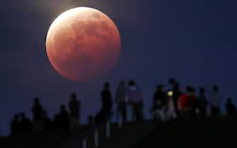 epa09230583 People watch the total eclipse of the moon at Moerenuma Park in Sapporo, northern Japan, 26 May 2021, as the super moon is passing through the shadow of the earth.  EPA/JIJI JAPAN OUT EDITORIAL USE ONLY/  NO ARCHIVES