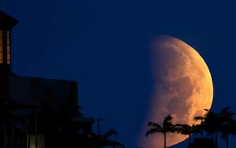The partially eclipsed moon sets over West Palm Beach Wednesday morning, May 26, 2021. The moon was near its closest approach to Earth, making it a "supermoon," and meaning it appears slightly larger in the sky. (Photo by Lannis Waters/Palmbeachpost/USA Today Network/Sipa USA)