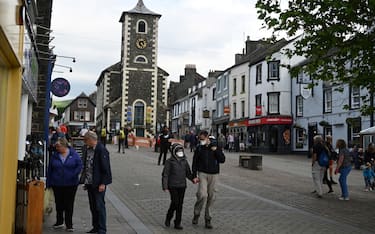 Pedestrians wearing face coverings due to Covid-19 walk past shops in Keswick in Cumbria, north west England on June 21, 2021. (Photo by Oli SCARFF / AFP) (Photo by OLI SCARFF/AFP via Getty Images)