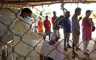 Un operatore sanitario effettua un tampone per la rilevazione del coronavirus a una donna a Bangalore, in India