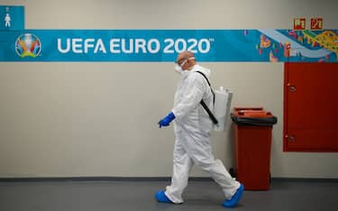 27 June 2021, Hungary, Budapest: Football: European Championship, Netherlands - Czech Republic, final round, round of 16, at the Puskas Arena. A man in protective clothing and a container of disinfectant on his back walks through the press room. Photo: Robert Michael/dpa-Zentralbild/dpa - IMPORTANT NOTE: In accordance with the regulations of the DFL Deutsche Fußball Liga and/or the DFB Deutscher Fußball-Bund, it is prohibited to use or have used photographs taken in the stadium and/or of the match in the form of sequence pictures and/or video-like photo series.