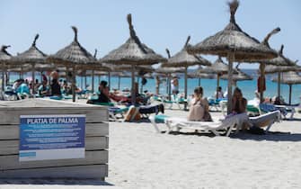 26 June 2021, Spain, Palma de Mallorca: Tourists sunbathe on the beach of Arenal. The mask requirement has been considerably relaxed in Spain. Mouth-nose protection no longer has to be worn outdoors at all times and in all places. Photo: Clara Margais/dpa (Photo by Clara Margais/picture alliance via Getty Images)