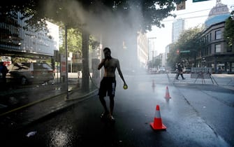 A resident walks through a temporary misting station on Abbott Street during a heatwave in Vancouver, British Columbia, Canada, on Monday, June 28, 2021. The heat is expected to continue for several days in some parts of British Columbia, according to weather warnings from the government. Photographer: Trevor Hagan/Bloomberg
