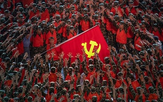 BEIJING, CHINA - JUNE 28: Performers in the costume of emergency workers surround a large Communist Party flag during a mass gala marking the 100th anniversary of the Communist Party on June 28, 2021 at the Olympic Bird's Nest stadium in Beijing, China. China will officially mark the100th anniversary of the founding of the Communist Party on July 1st. (Photo by Kevin Frayer/Getty Images)