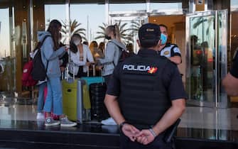 Giovani con le valigie e un poliziotto davanti a un hotel di Maiorca, in Spagna