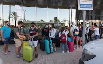 Giovani con le valigie in attesa davanti a un albergo di Maiorca, in Spagna