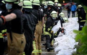 epa09344866 Firefighters and the technical relief organization move sandbags against the rising water level of the Duessel, which has already flooded large parts and streets, in Duesseldorf Grafenberg, Germany, 14 July 2021. Large parts of North Rhine-Westphalia were hit by heavy, continuous rain in the night to 14 July. According to the German Weather Service (DWD), the rain is not expected to let up until 15 July. The Rhine level has risen significantly in recent days.  EPA/SASCHA STEINBACH