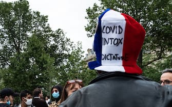 A demonstrator is wearing a hat with the colors of France, blue, white, red, on which can be read "COVID, Intox, Dictatorship", while July 14, 2021, 2 days after the last speech of the President of the French Republic Emmanuel Macron to establish the mandatory vaccination of caregivers and the generalization of the Health Pass in public places of more than 50 people to cope with an upsurge of Covid in France following the emergence of the Delta variant, several hundred people gathered in the streets of Paris to demonstrate their opposition. This demonstration was quickly repressed by the riot police creating clashes with the demonstrators, many of whom claimed to be Yellow Vests. (Photo by Samuel Boivin/NurPhoto)